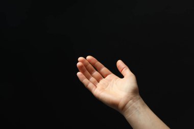 Siyah arka planda elinde bir şey tutan bir kadın, yakın plan. Metin için boşluk
