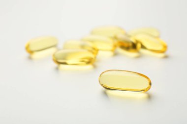 Beyaz arkaplanda sarı vitamin kapsülleri, yakın plan