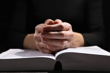 Din. Hıristiyan kadın masada İncil için dua ediyor, yakın plan.