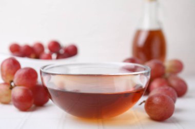 Cam kasede şarap sirkesi ve beyaz masada üzüm, yakın plan.