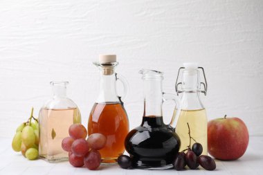 Different types of vinegar and ingredients on light tiled table, closeup clipart