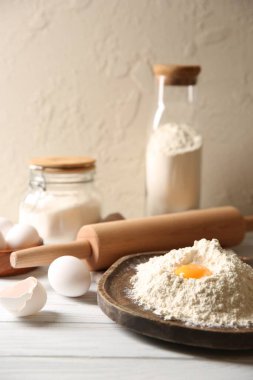 Para kazanmak. Sarısı olan un yığını, yuvarlanan iğne ve yumurtalar beyaz ahşap masada, yakın plan.