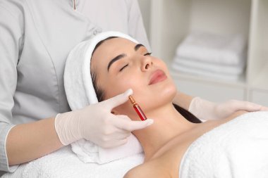Klinikte müşteriyle çalışırken cilt bakımı yapan profesyonel bir kozmetikçi.