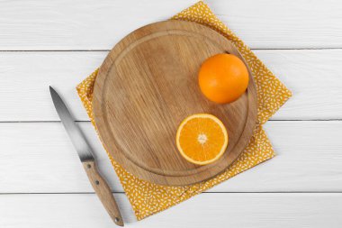 Kesme tahtası, portakal, bıçak ve peçete beyaz ahşap masa, üst manzara
