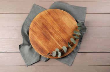 Kesme tahtası, okaliptüs dalı ve bej ahşap masa üzerinde peçete.