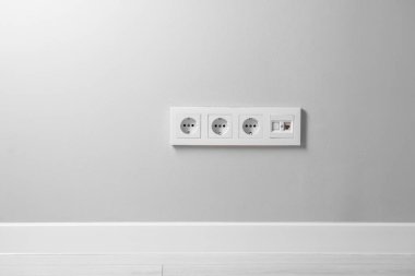 Açık gri duvardaki elektrik prizleri kapalı alanda.
