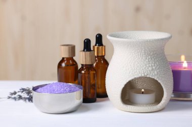 Farklı aromaterapi ürünleri ve beyaz ahşap masada mum yakmak.