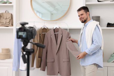 Gülümseyen moda blogcusu evde video kaydederken kıyafetlerini gösteriyor