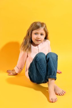 Moda konsepti. Sarı arka planda poz veren şık kız.