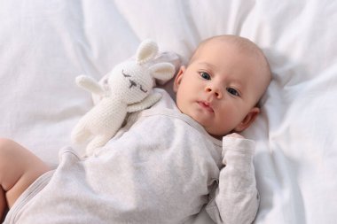 Beyaz çarşafların üzerinde uzanmış, sevimli, küçük bir bebek.