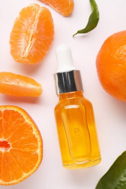 Aromatik mandalina yağı şişede ve turunçgiller beyaz masada, düz yerde.