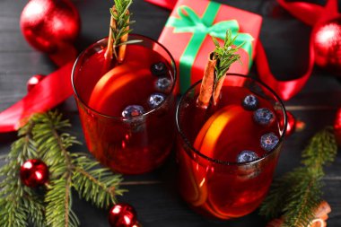 Kadehler, malzemeler ve siyah ahşap masa üzerindeki Noel dekoruyla Aromatik Sangria içeceği.