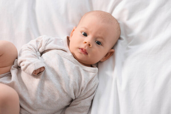 Милый малыш лежит на белых простынях, вид сверху