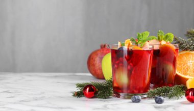 Beyaz mermer masada, bardaklarda, malzemelerde ve Noel dekorunda Aromatik Sangria içeceği, metin için yer