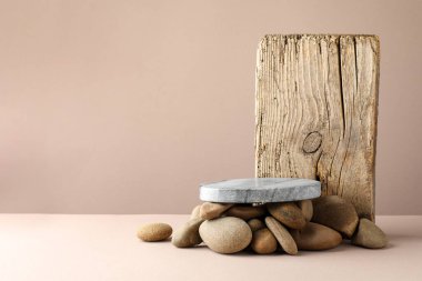 Ürün sunumu. Taş podyum ve bej arka planda çakıl taşları. Metin için boşluk