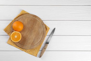Kesme tahtası, portakal, bıçak ve peçete beyaz ahşap masa, üst manzara. Metin için boşluk