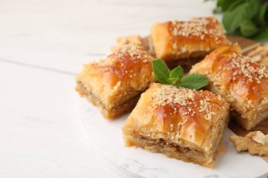 Doğu tatlıları. Beyaz ahşap masadaki lezzetli baklava parçaları, yakın plan. Metin için boşluk