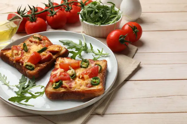 Tasty pizza toasts and ingredients on light wooden table
