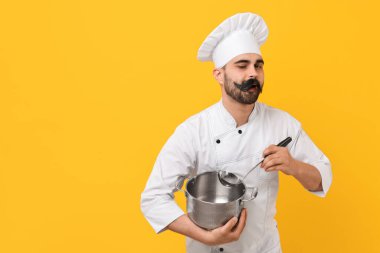 Profesyonel şef, komik yapay bıyıklı, sarı arka planda tencere ve kepçe tutan. Metin için boşluk
