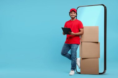 Açık mavi arka planda kocaman bir akıllı telefonun yanında paket ve pano yığını olan bir kurye. Teslimat servisi. Metin için boşluk