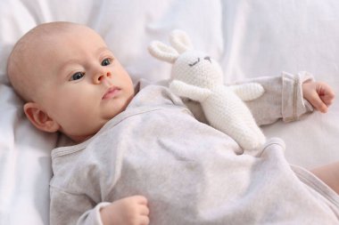 Beyaz çarşaflara uzanmış oyuncak gibi tatlı bir bebek.