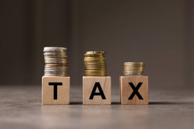 Sözcük vergisi gri masadaki tahtadan harfler ve paralardan oluşuyor.