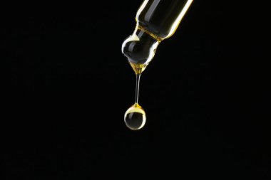 Siyah arka planda pipetten tentür damlatıyor, yakın plan. Metin için boşluk