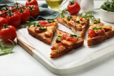 Lezzetli pizza tostları ve malzemeler beyaz mermer masada, yakın plan.
