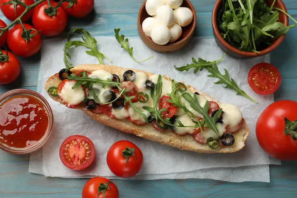 Tasty pizza toast and ingredients on light blue wooden table, top view