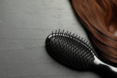 Kahverengi saç telli, koyu gri masadaki şık fırça, üst manzara. Metin için boşluk