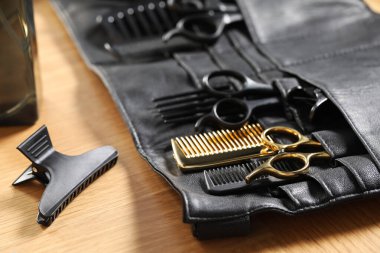 Kuaför aletleri. Profesyonel makas ve taraklar deri düzenleyiciyle ahşap masada, yakın plan.