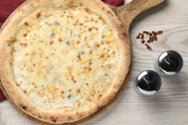 Lezzetli peynirli pizza, beyaz ahşap masada tuzluk ve biber.