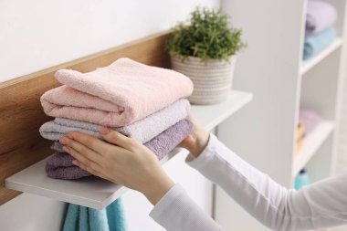 Kadın temiz havluları evin içinde diziyor, yakın plan.