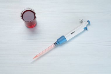 Laboratuvar analizi. Beyaz ahşap masa üzerinde sıvı bulunan mikro pipet ve beher.