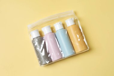 Sarı arka planda plastik çantada kozmetik seyahat kiti, üst görünüm