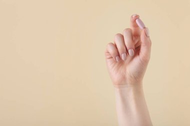 Bej arka planda vitamin hapı tutan bir kadın, mesaj için yeri olan bir kadın. Sağlık takviyesi
