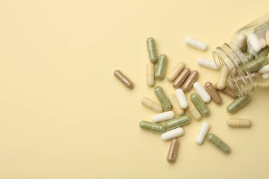 Bej arka planda vitamin hapları ve şişe, üst manzara. Metin için boşluk