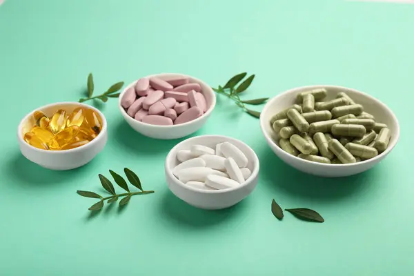Different Vitamin Capsules Bowls Leaves Turquoise Background Stok Gambar