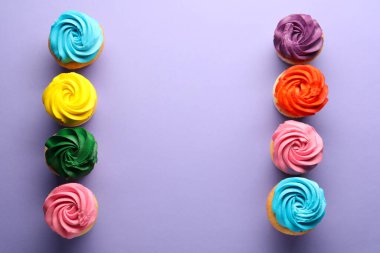 Menekşe arkaplanda parlak kremalı leziz kekler, düz konum. Metin için boşluk