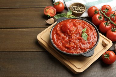 Ev yapımı domates sosu kasede ve malzemeler ahşap masada, metin için yer var.