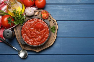Ev yapımı domates sosu kasede, kaşık ve malzemeler mavi ahşap masada, düz yerde. Metin için boşluk