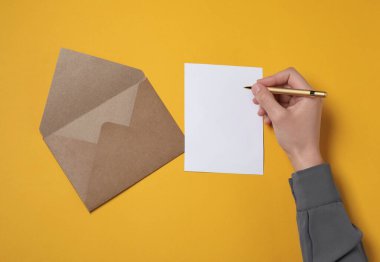 Turuncu masada mektup yazan bir kadın. Metin için boşluk