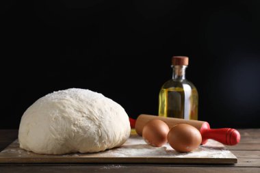 Çiğ hamur, merdane ve malzemeler ahşap masada.