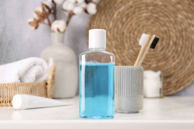 Banyodaki beyaz masada bir şişe gargara ve diş fırçası.