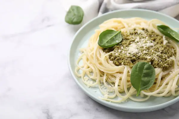 Tasty pasta with spinach, cheese and sauce on white marble table. Space for text