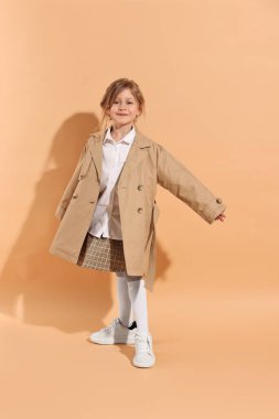Moda konsepti. Soluk turuncu arka planda poz veren şık kız.