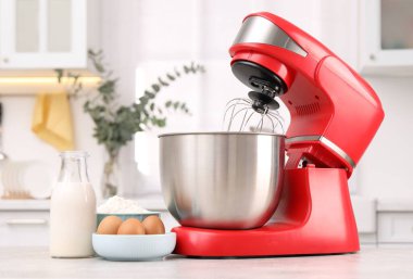 Modern kırmızı stand mikseri ve ürünler açık gri mutfak masasında