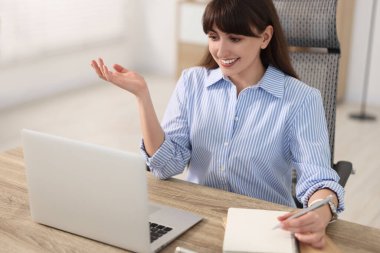 İçerideki ahşap masada giysi giyerken not alan kadın.