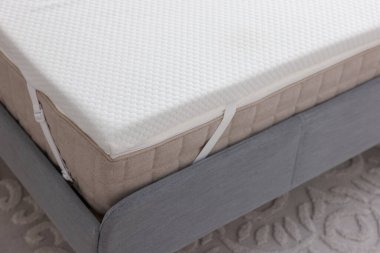 Gri yatakta beyaz köpüklü döşek.