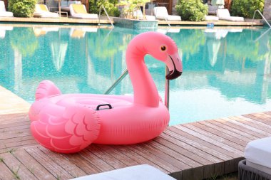 Lüks bir tatil köyünde yüzme havuzunun yanındaki tahta güvertede flamingo şeklinde süzül.